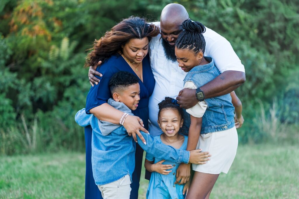 What is Financial Stability in Family. A picture showing a man, woman and  three  children tightly connected with a hug.