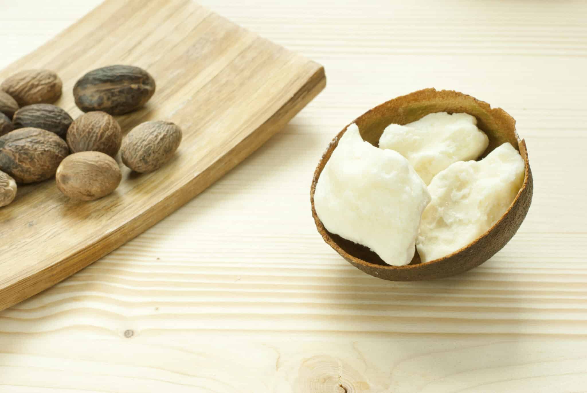 Raw African Shea Butter in a local bowl and Nuts on a brown board.