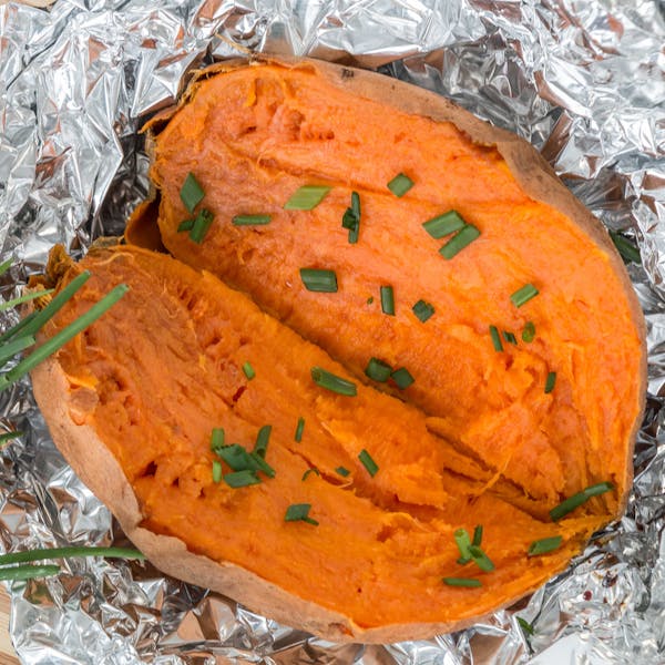 Boiled Sweet potatoes placed on an aluminium foil with sprinkled spring onions