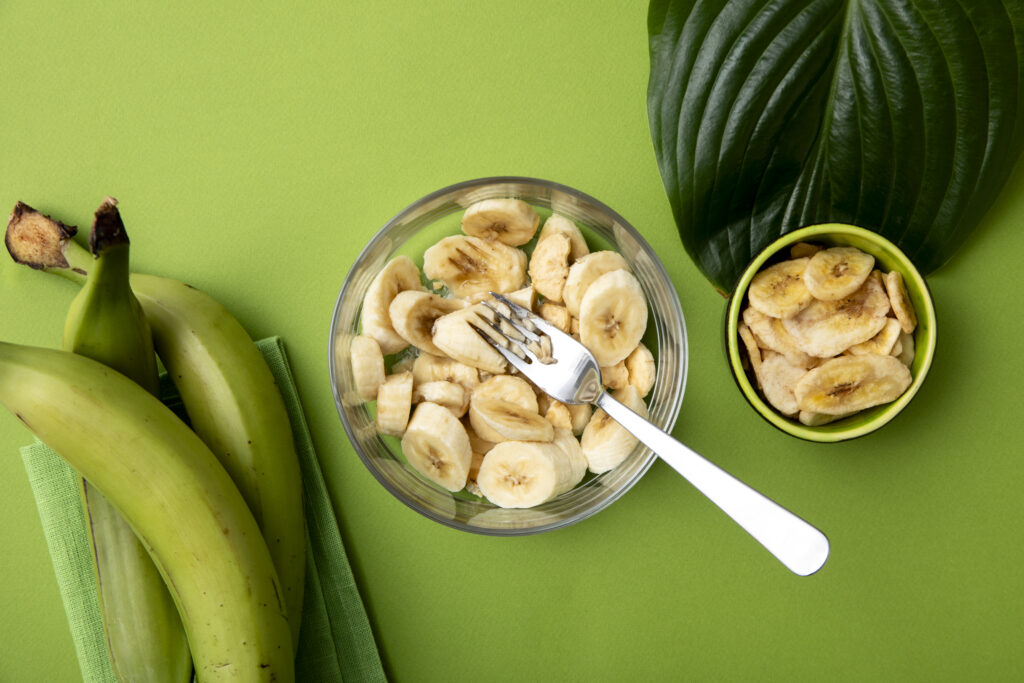 Green plantains sliced in a transparent bowl for cooking.