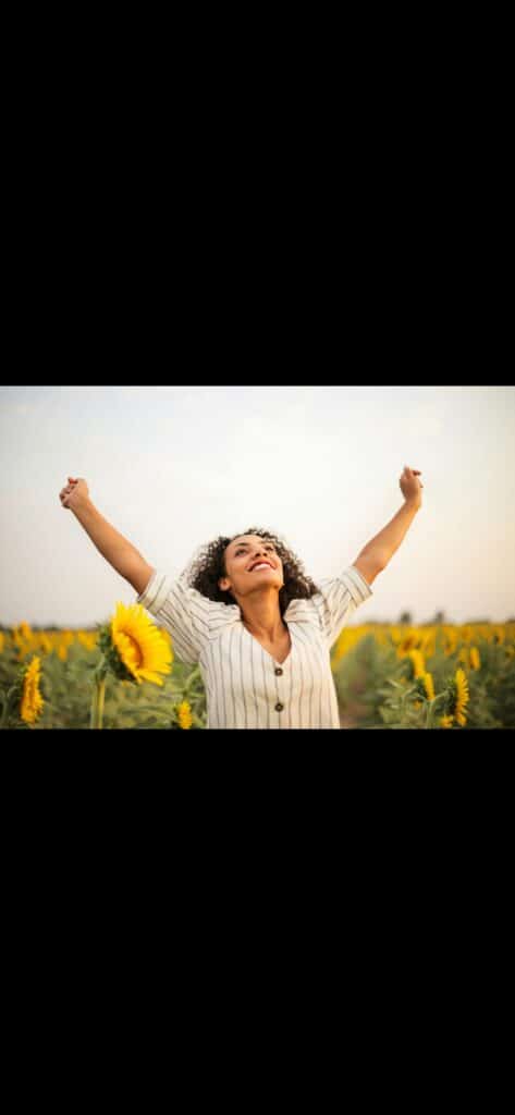 A happy and vibrant woman taking a walk in the park with lots of beautiful sun flowers around her/